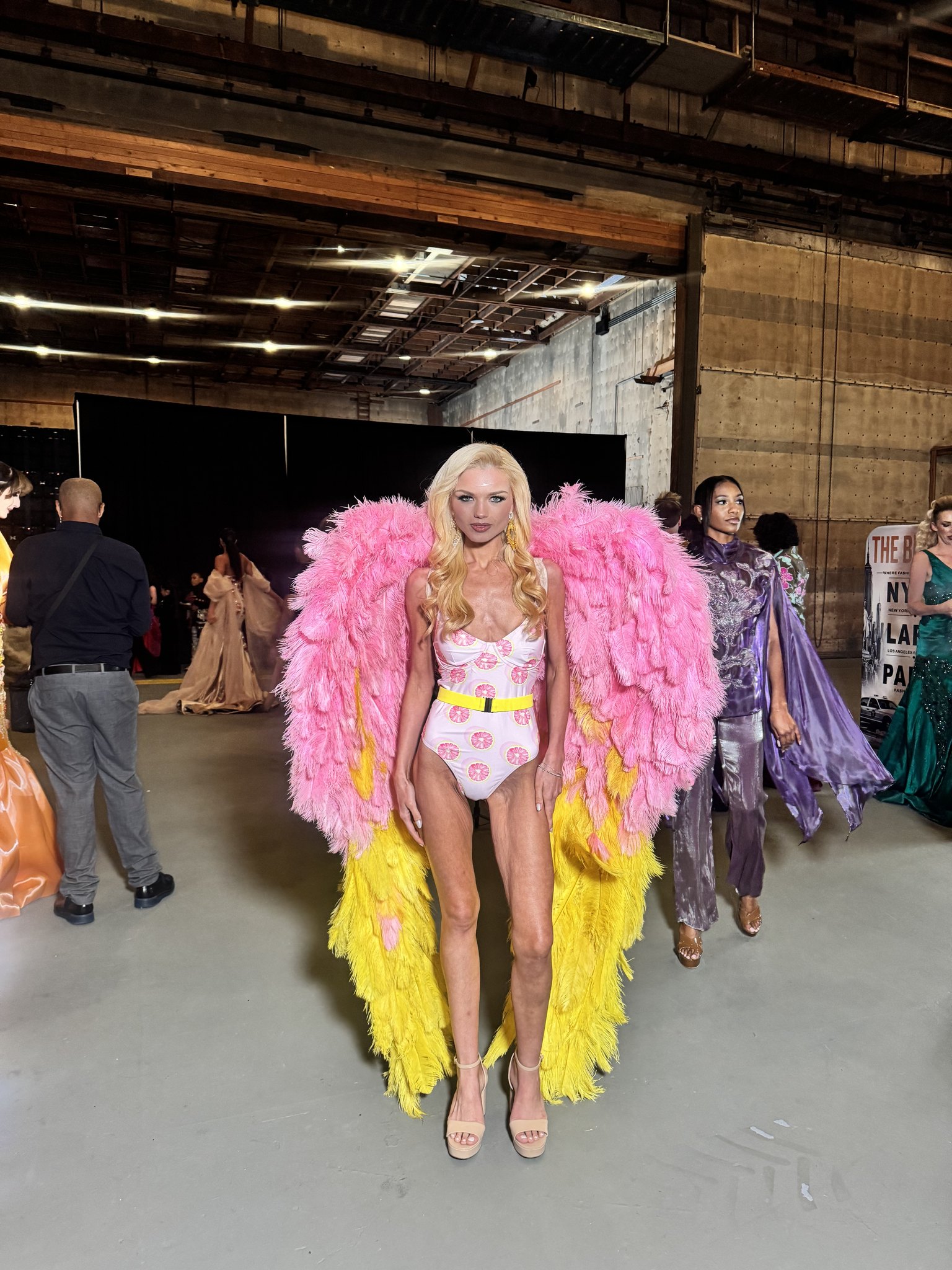 Emily Sophie Christine behind the scenes at The Bureau Fashion Week LA in pink and yellow feathered wings