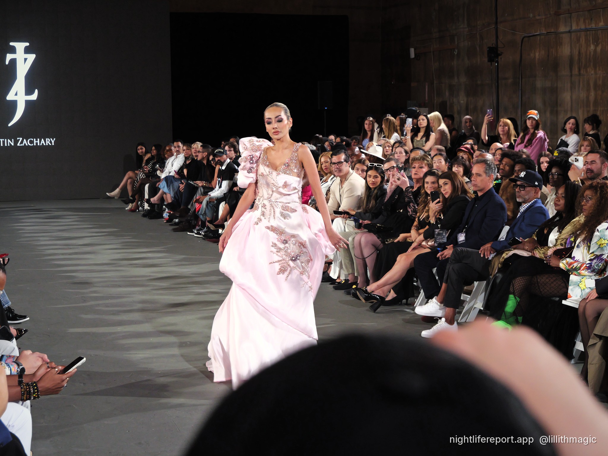 Mirka Howard (@mirhoward28) walks Justin Zachary Look 13, a blush floral-embroidered gown with a ruffled shoulder, at The Bureau Fashion Week LA, Day 2, The Finale, Sat Oct 17, 2026 (frame P1000962). Photo: Anthony Perlas / nightlifereport.app