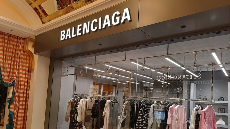 Balenciaga boutique storefront with the brand's sign above a window of clothing racks