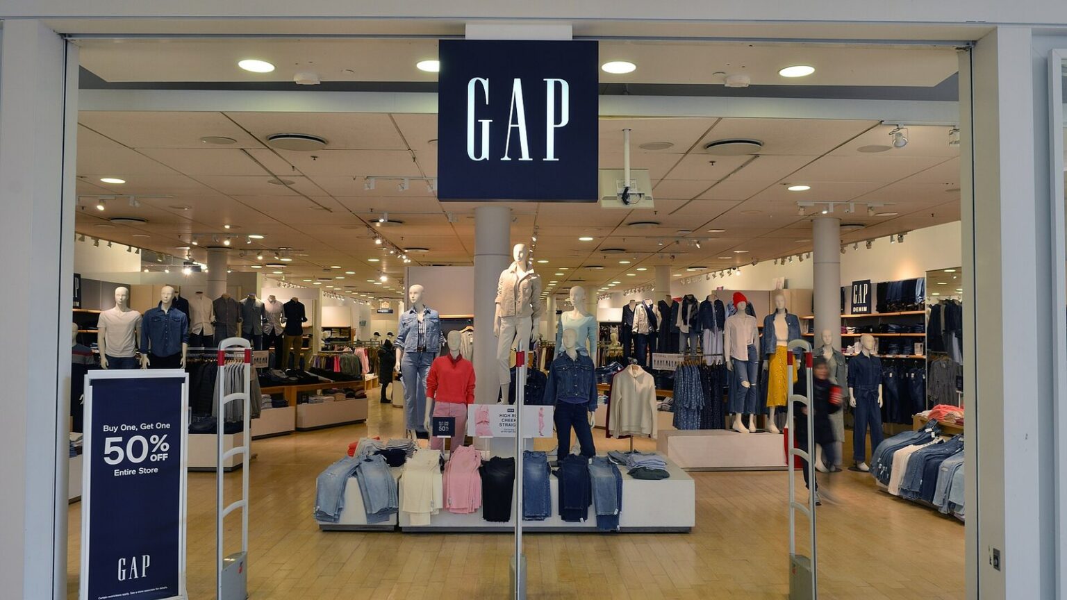 Entrance of a Gap store with the Gap logo above the doors and denim displays inside