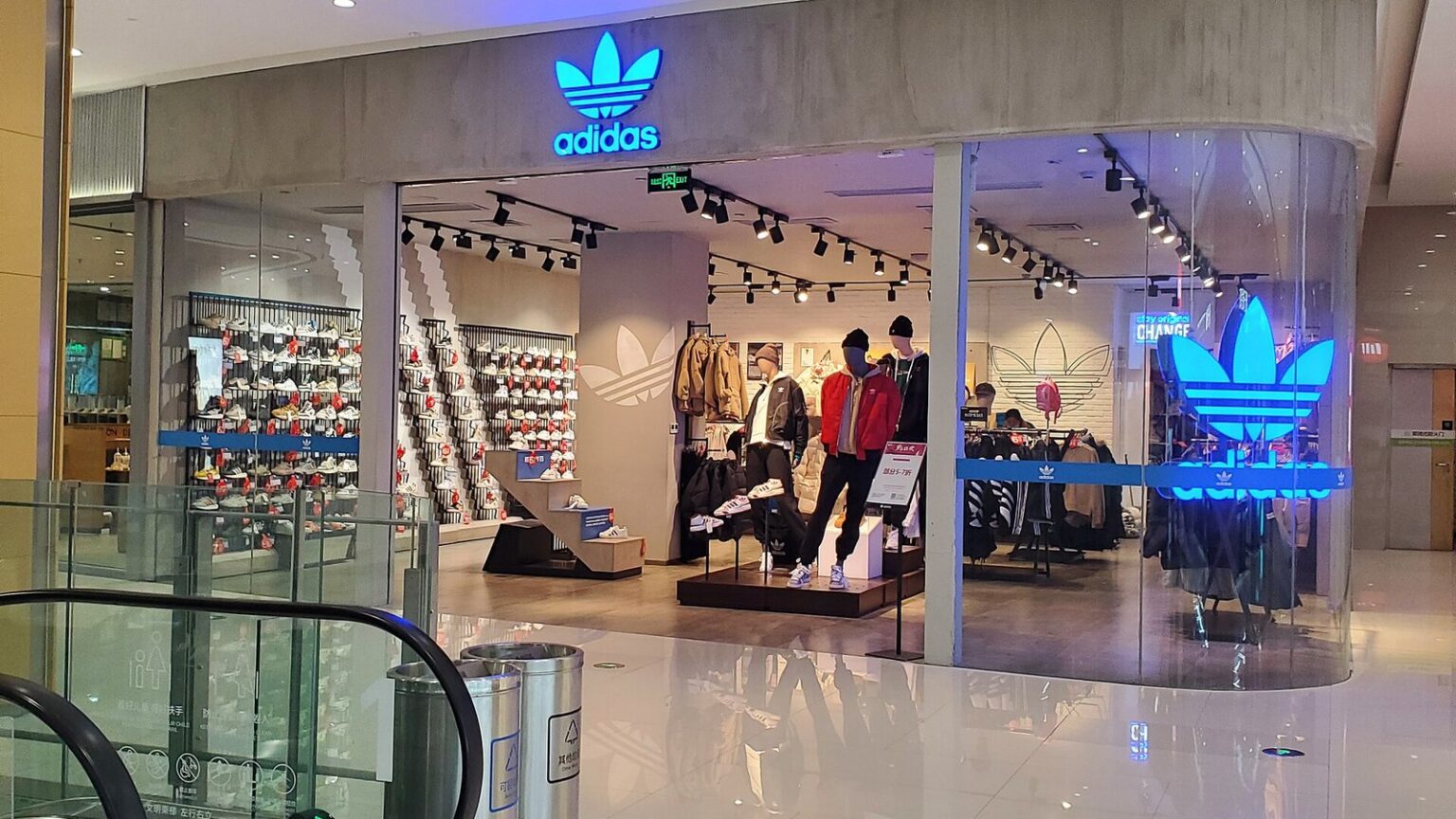 adidas Originals store with a glowing blue trefoil logo and tracksuits on display