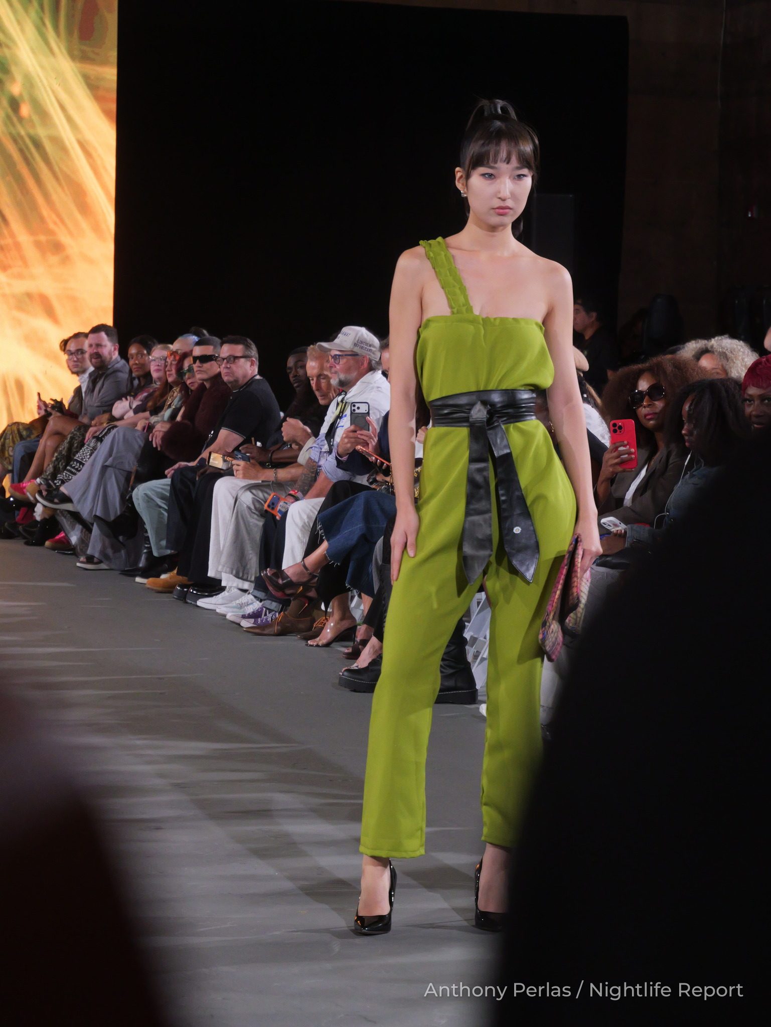 Runway look by Sewreffic at The Bureau Fashion Week LA, The Opening: lime green one-shoulder jumpsuit with a black sash belt.