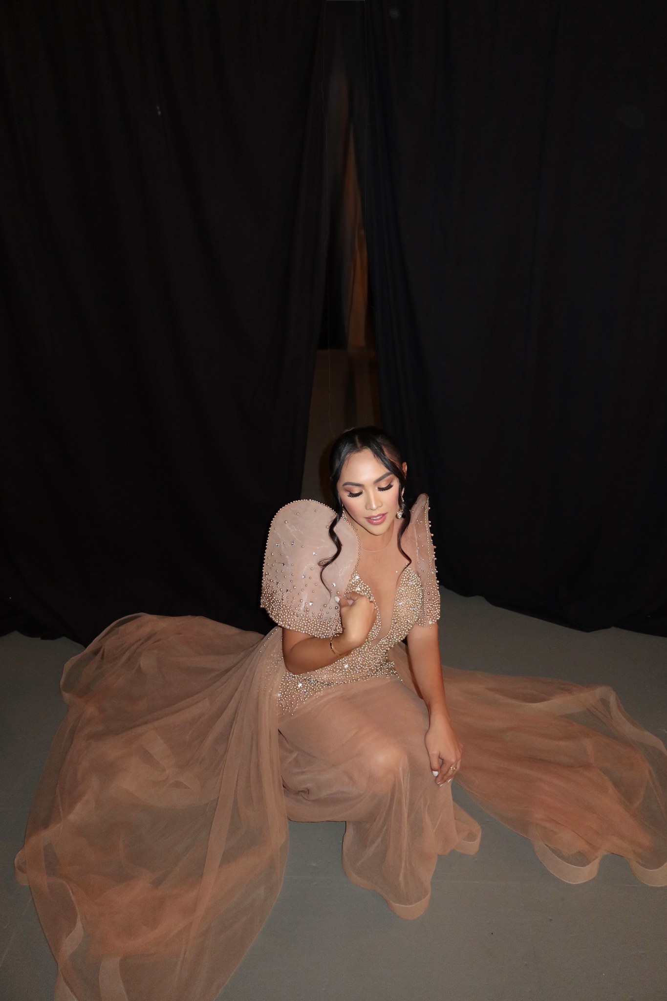 Sofhia Flores seated in a gown against a dark curtain