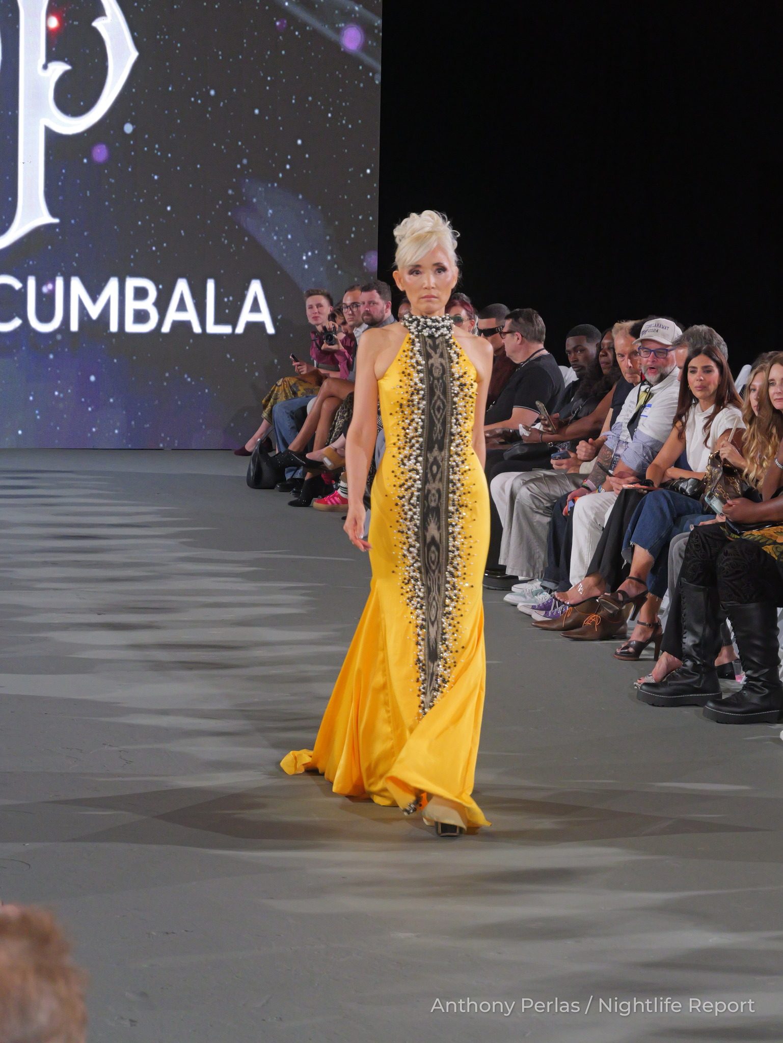 Runway look by Toshimi Pacumbala at The Bureau Fashion Week LA, The Opening: marigold column gown with a long black and gold beaded front panel.